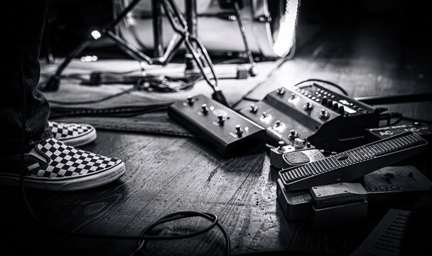 Guitarist pedalboard on a live concert stage next to his feet. Intimate classic rock gig.