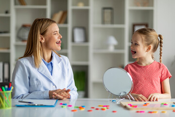 Child Specialist Making Tongue Exercises During Speech Therapy Session With Little Girl