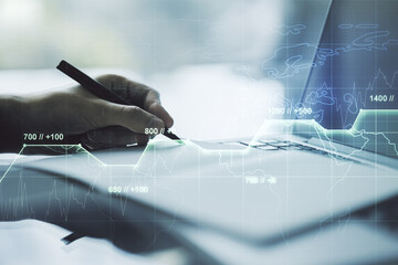 Double exposure of abstract creative statistics data hologram with hand writing in notepad on background with laptop, analytics and forecasting concept