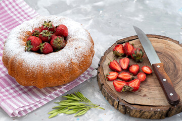 a top view round cake with sugar powder red strawberries on the white desk berry fruit cake