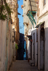 Street scene in the Casbah of Algiers (Alger), Algeria. Cobblestone grounf and ancient ottoman houses. Narrow street and the mediterranean sea in the background.