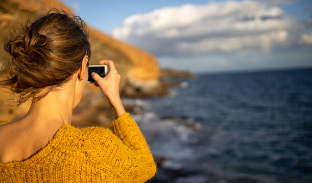 Pretty, young woman taking photos with her smartphone during her vacation