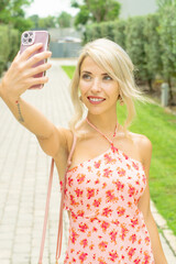PRETTY GIRL SMILING WHILE IS TAKING A SELFIE AND CALLING BY PHONE IN THE STREET