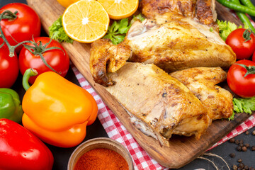 bottom view baked chicken tomatoes lemon slices on wood board bell peppers on table