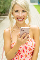 PRETTY GIRL SMILING WHILE IS TAKING A SELFIE AND CALLING BY PHONE IN THE STREET
