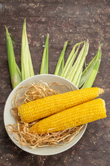top view fresh yellow corns inside white plate on the wooden desk food meal raw color