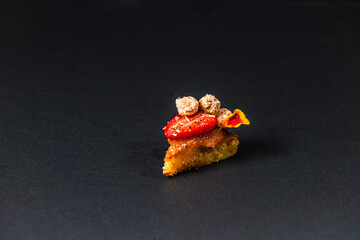 focus on gastronomic appetizer made of strawberry and nuts and cake isolated on a black background