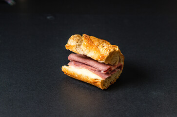 Fresh French sandwich with ham and butter, classic 'jambon beurre' from Paris isolated on a black background