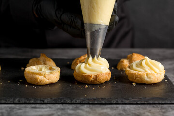A confectionery sleeve is used to fill profiteroles with cream