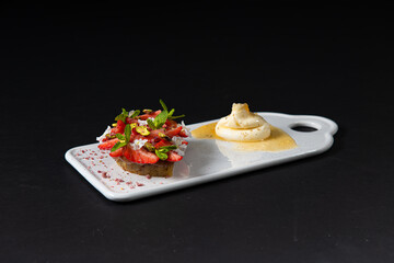 Gastronomic delights of restaurant dishes, strawberry pie  dessert with ice cream on a white rectangular plate isolated on a black background, culinary arts