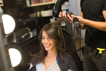 Young woman getting new hairstyle from hairdresser in the modern hair salon