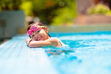 Child in swimming pool on ring toy. Kids swim.