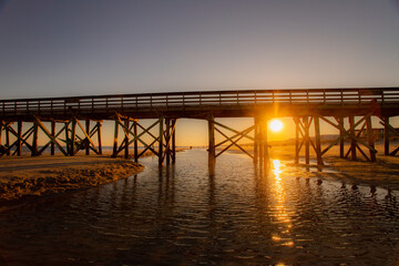 Sunset Light Shining Through Wooden Bridge Over Coastal Water
