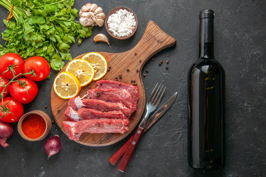 top view raw meat slices with greens lemon tomatoes and seasonings on dark background meal dinner meat animal butcher salad barbecue