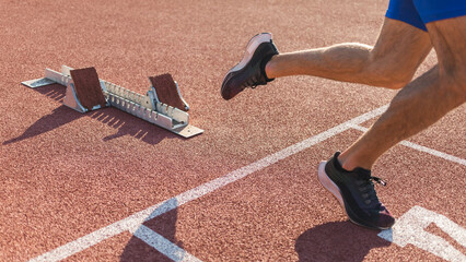 Young man training for run race start on a stadium track outside