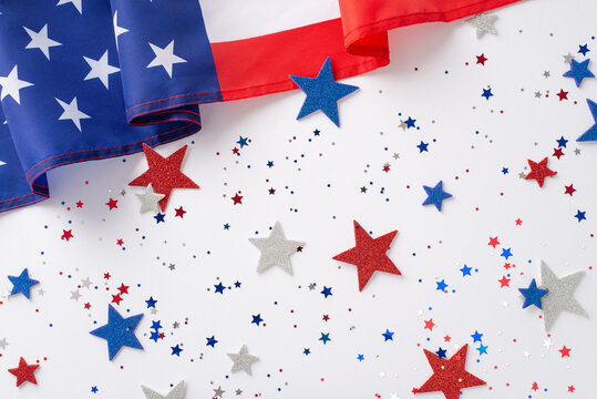 US Independence Day concept. Top view photo of blue, white and red star-shaped confetti and american flag at the top on white isolated background