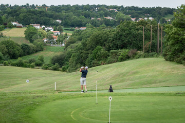 Obraz premium Golfista a meio de um campo de golfe a dar a tacada na bola num dia muito nublado