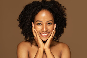 Beautiful young black woman touching her pretty face and smiling