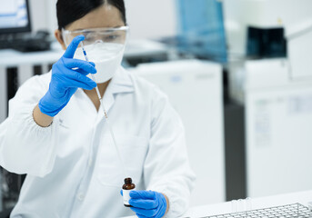 Selective focus woman scientist wearing blue gloves hand holding and using pipette drop reagent for...