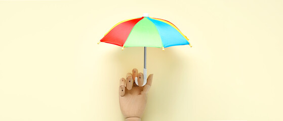 Wooden hand and mini umbrella on beige background