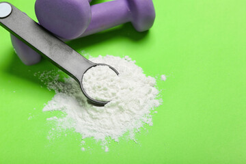 Scoop of amino acid supplement and dumbbells on color background