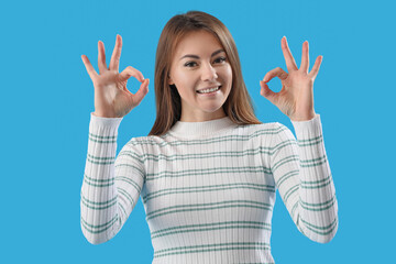 Beautiful woman showing OK on blue background