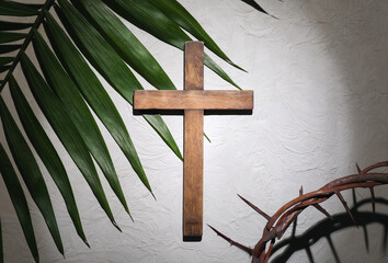 Fototapeta na wymiar Crown of thorns with wooden cross and palm leaf on light background. Good Friday concept