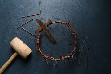 Crown of thorns with wooden cross, mallet and nails on dark background. Good Friday concept