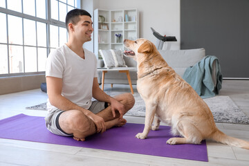 Young man with cute Labrador dog training at home