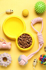 Composition with bowl of wet food and pet care accessories on yellow background