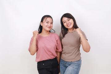 Two confident asian women standing while clenching hands. Isolated on white background
