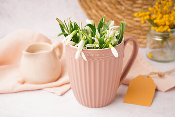 Cup with beautiful snowdrops on grey table