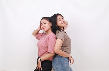 Two pretty woman standing back to back on white background. Friendship concept