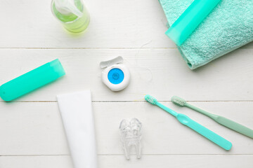 Composition with dental floss, brushes, toothpaste and rinse on white wooden table