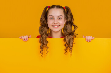 happy kid behind blank yellow paper with copy space for advertisement
