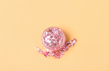 Jar of pink glitter on beige background