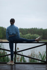 Fototapeta premium View of a girl with athletic body in blue gym suit is doing exercises in the park in cloudy weather.