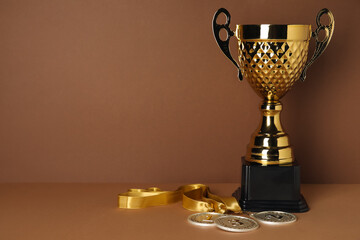 Gold cup with prize medals on brown background