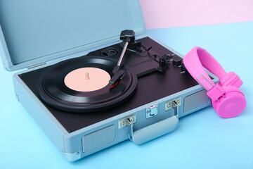 Obraz premium Record player with vinyl disk and headphones on table near pink wall