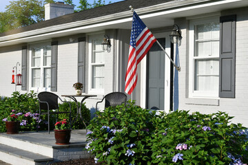 Front porch of a gray ranch house with an American flag 