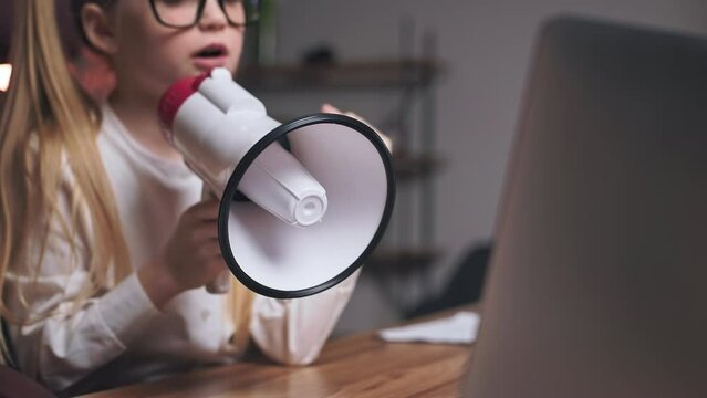 Strict and angry child taking disciplinary action with company workers for doing bad work. Little entrepreneur in glasses yelling in loudspeaker during online conference on portable laptop.