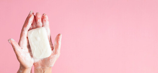 Washing of hands with soap. Cleaning hands. Closeup on woman hands with soap bar on pastel pink...