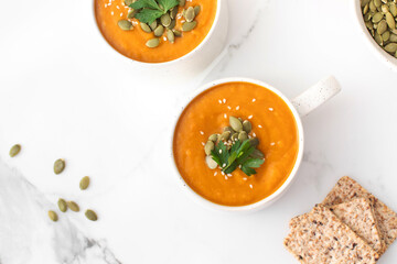 Mugs of warm pumpkin soup. The concept of the autumn menu. Autumn recipes.