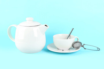 Teapot, cup and infuser on blue background
