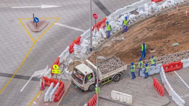 Process of sidewalk road repairing with many builder workers and equipment breaking pavement and concrete. Loading in cargo truck at construction site. Aerial timelapse of new walkway works in Dubai
