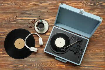 Record player with vinyl disks, headphones and cup of coffee on wooden background