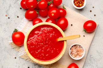 Bowl with tasty tomato sauce and fresh vegetables on grunge background