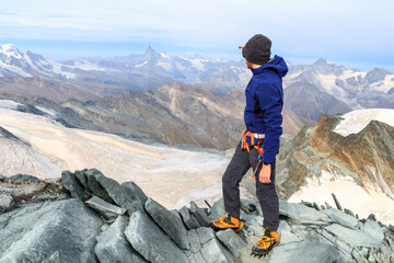 Mountaineer man standing on summit of mountain Allalinhorn and looking to panorama view with...