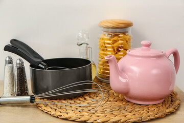 Composition with teapot and different kitchen stuff on white table