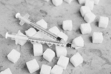 Sugar cubes with syringes for insulin injection on grunge background, closeup